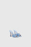 Elegante paio di scarpe modello mule con tacco alto azzurro con dettagli in cristallo, mostrate su sfondo chiaro che ne esalta il design lussuoso