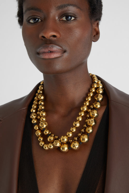 Three-strand necklace of gold metal pearls