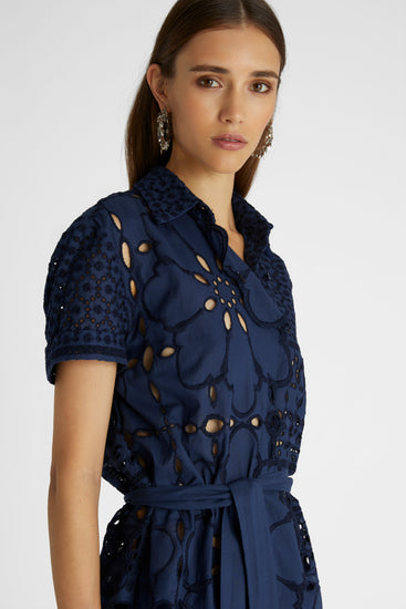 Close-up of model in navy broaderie anglaise short sleeve cotton shirt with a sash at waistline