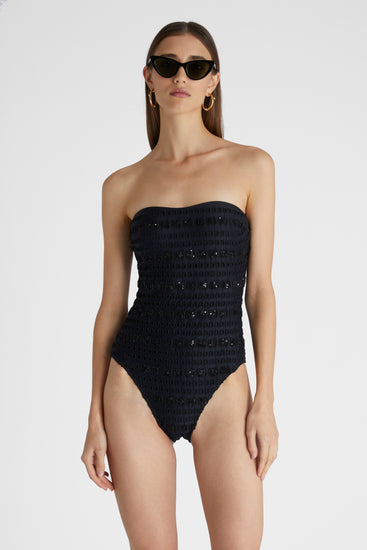 Model in black one-piece macramé swimsuit with removable straps and a sequin ribbon.